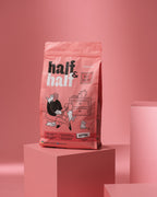 A colorful pink bag of Half&Half Kitten Food featuring a playful illustration of a person with kittens. The bag prominently displays the product name, Half&Half, and highlights the beef recipe, with a weight of 2 kg.
